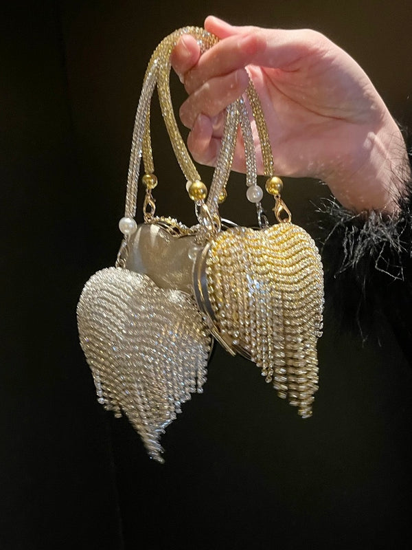 Hand holding a decorative chain bag heart-shaped against a dark background