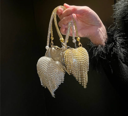 Hand holding a decorative chain bag heart-shaped against a dark background